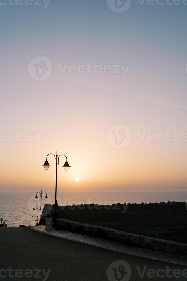 lanterne lungo il strada discendente per il mare a tramonto foto