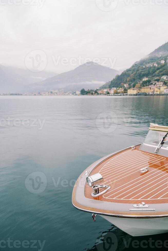 Marrone barca con un' lanterna su suo arco è ormeggiato su lago Como. Italia foto