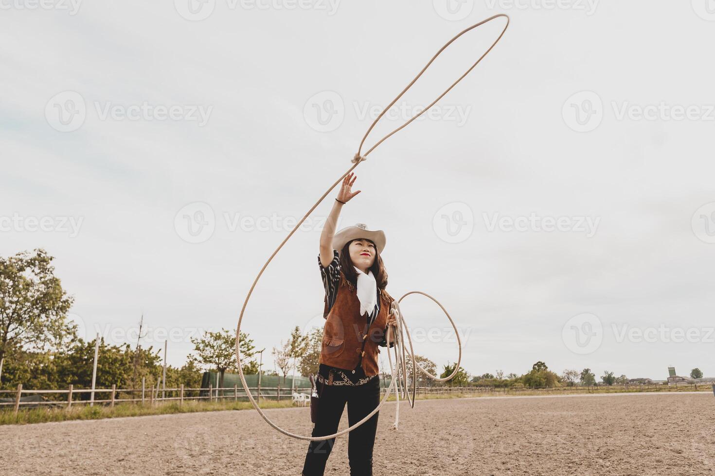 bella Cinese cowgirl lancio il laccio nel un' cavallo paddock foto