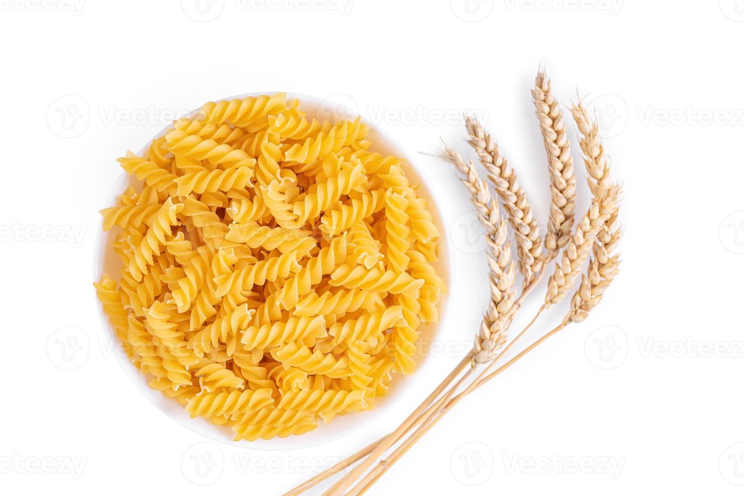 crudo pasta fusilli nel ciotola e Grano spighette isolato su bianca sfondo foto