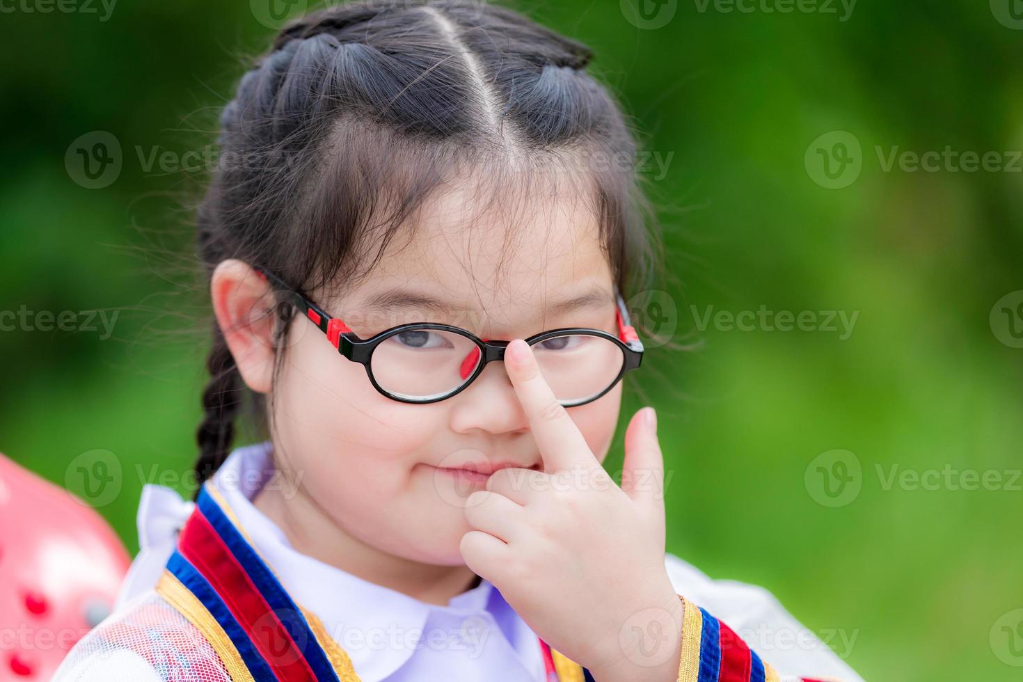 gli studenti dell'asilo spingono il dito indice al centro degli occhiali. bambino in età prescolare sorrise brillantemente. i bambini studiano. foto