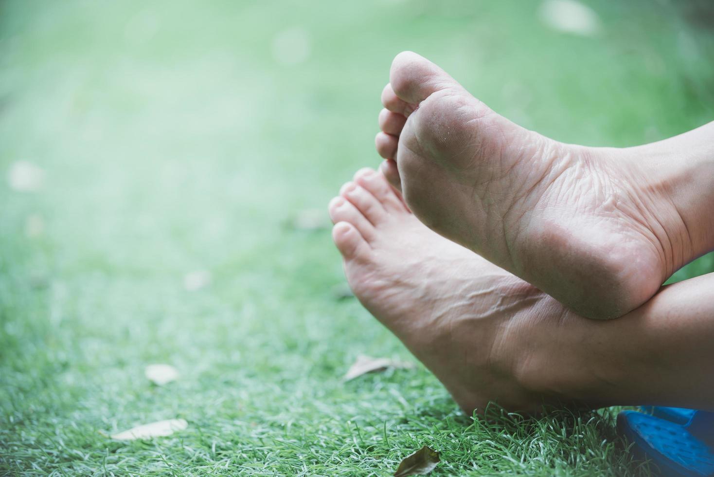 primi piani piedi di persone sedute sull'erba. le persone si tolgono le scarpe sull'erba. copia spazio. foto