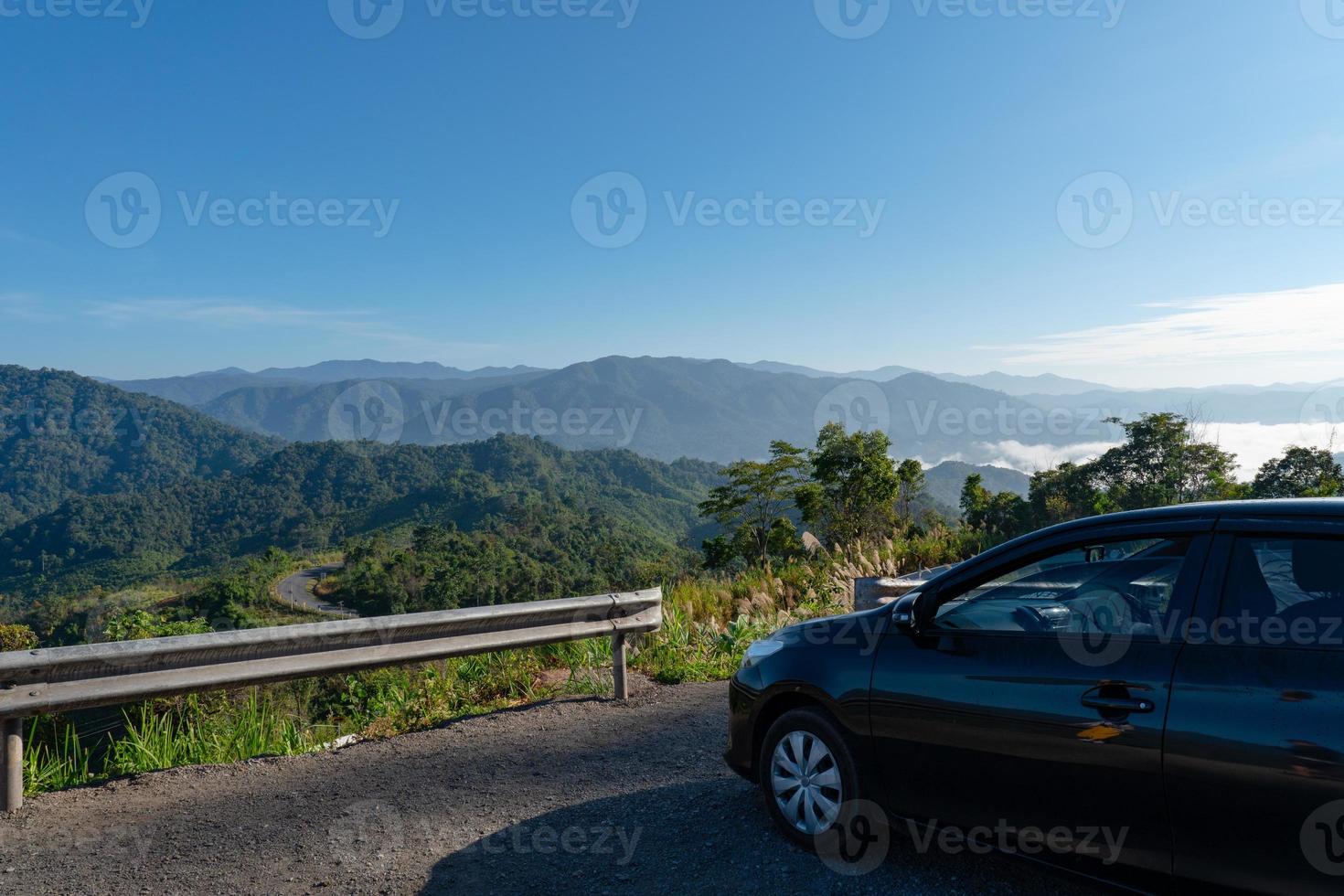 macchina nera parcheggiata sul lato della strada con bellissime montagne verdi e valle al mattino? foto