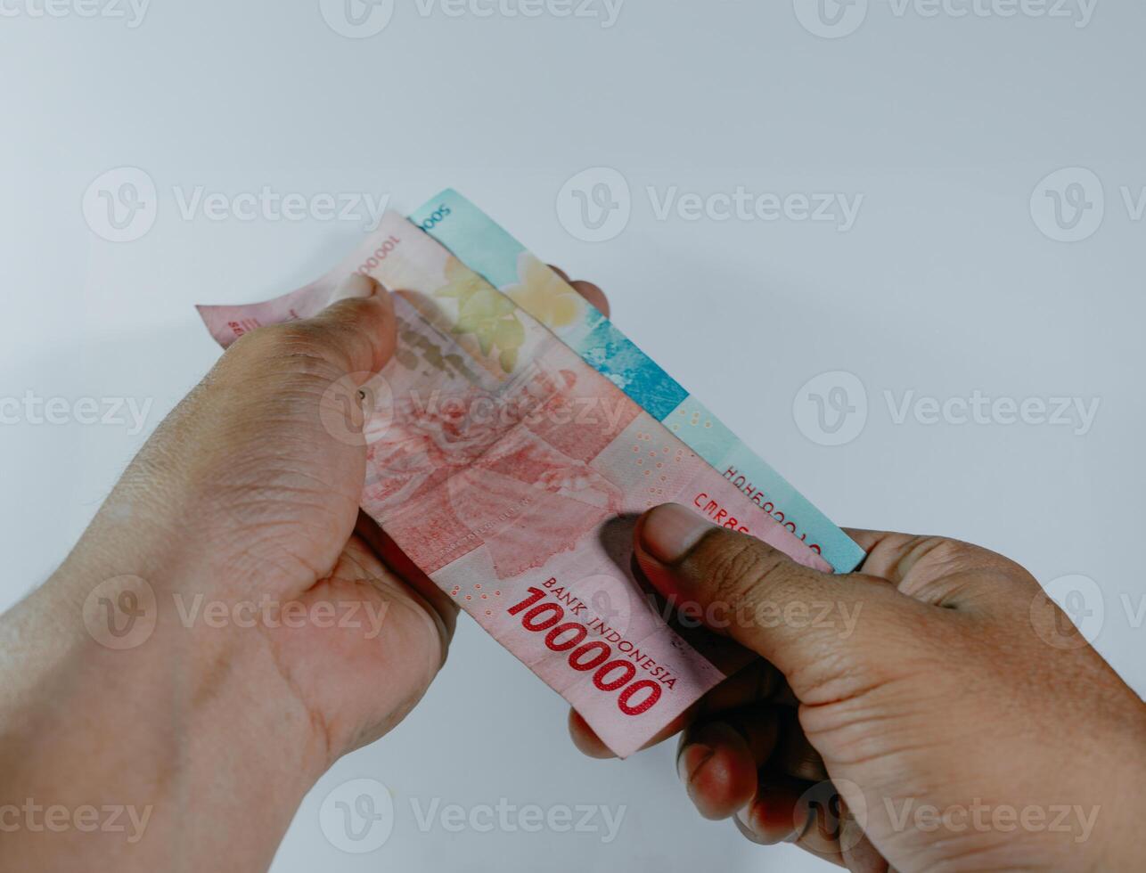 indonesiano moneta. mano Tenere 100.000 e 50.000 rupia banconote su un' bianca sfondo. foto