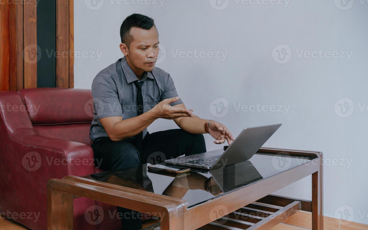 giovane uomo d'affari focalizzata Lavorando su computer portatile, utilizzando video chiamata con cliente su il computer portatile. giovane indonesiano uomo concentrandosi su dando in linea formazione scolastica classe lezioni, consulenza con clienti. foto