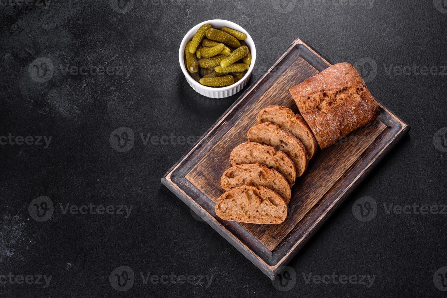 delizioso pane nero fresco affettato con fette su uno sfondo di cemento scuro foto