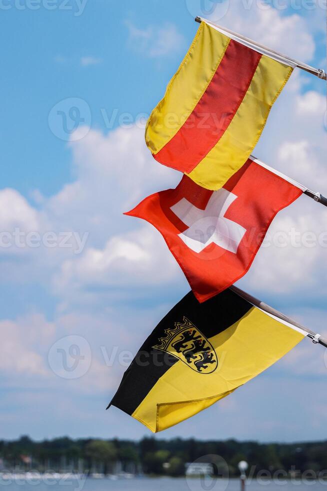 tre bandiere su il pennoni agitando nel il vento. bandiere di Baden, Svizzera, bandiera baden-wuerttemberg con un emblema. svizzero bandiera nel il mezzo. isolato su il blu cielo e bianca nuvole. copia spazio. foto