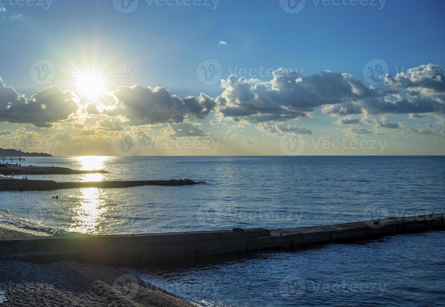 paesaggio marino con sole splendente su una spiaggia di ciottoli foto