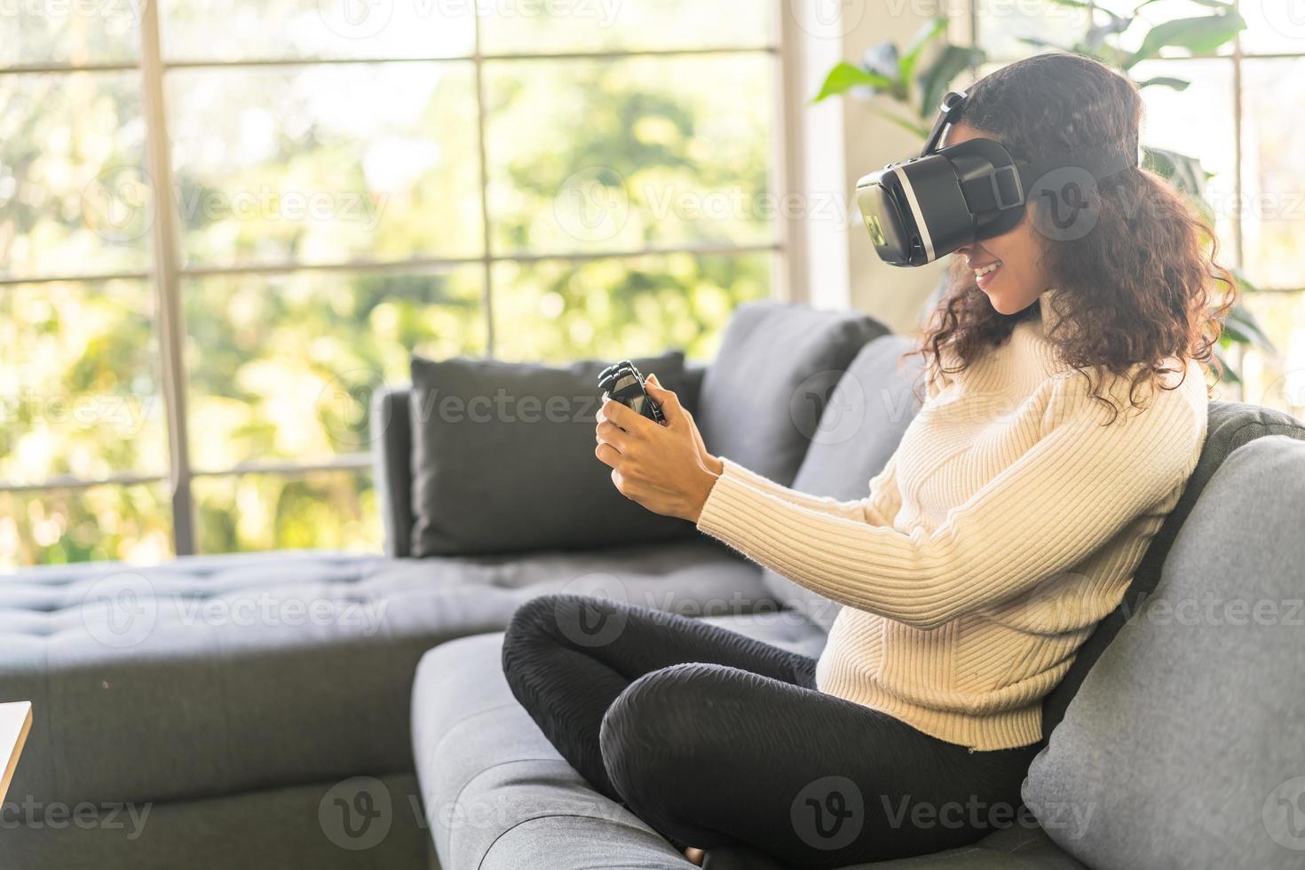 donna latina che utilizza un auricolare per realtà virtuale sul divano foto