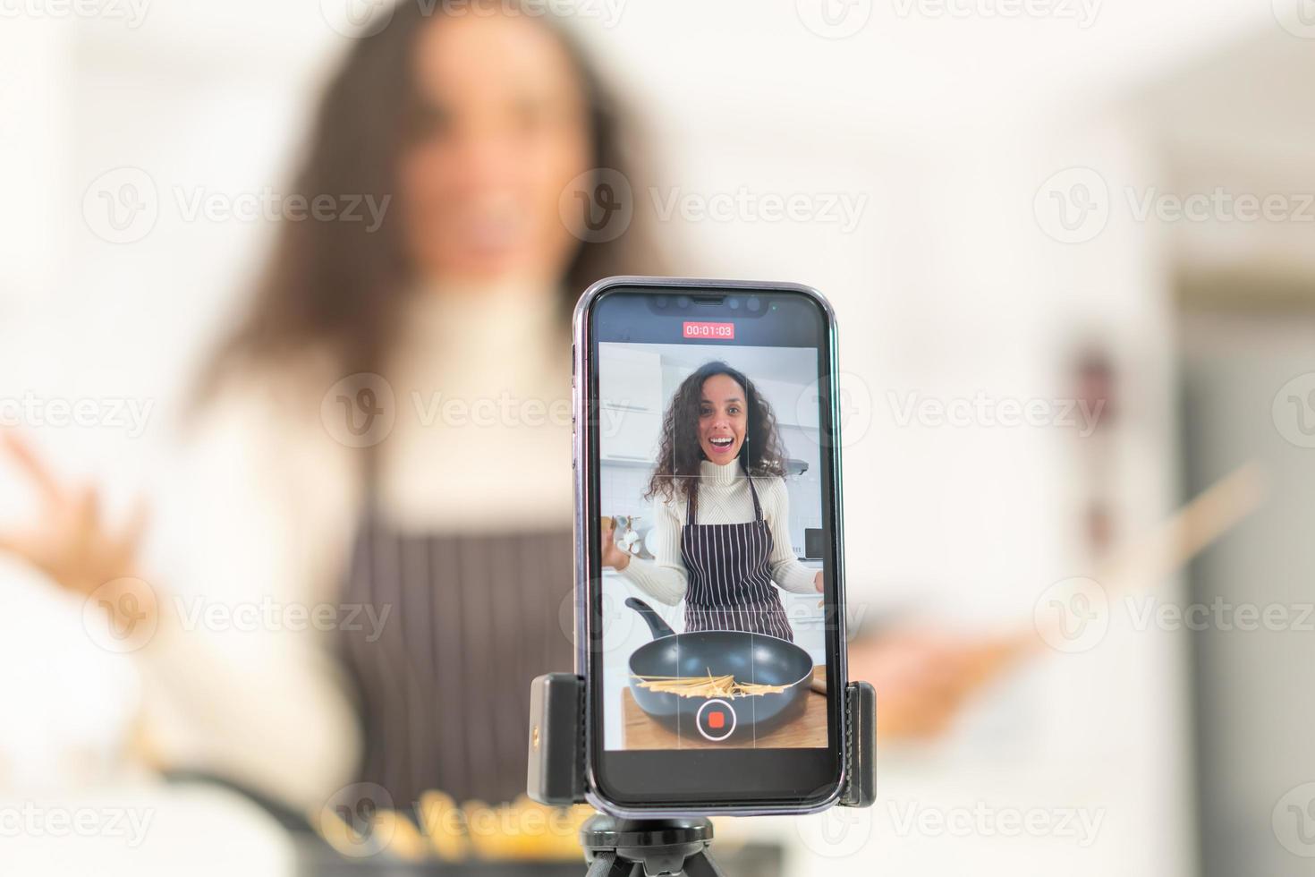 donna latina che gira video e cucina in cucina foto