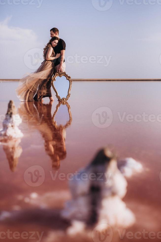 ragazza e un ragazzo sulla riva di un lago salato rosa foto