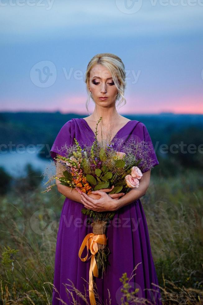 ragazza modella bionda in un abito lilla con un bouquet foto