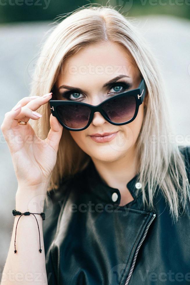 ragazza bionda in un tailleur pantalone nero con gli occhi azzurri sullo sfondo di una cava di granito foto