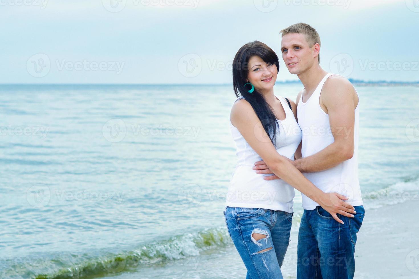 ragazzo e una ragazza in jeans e t-shirt bianche sulla spiaggia foto