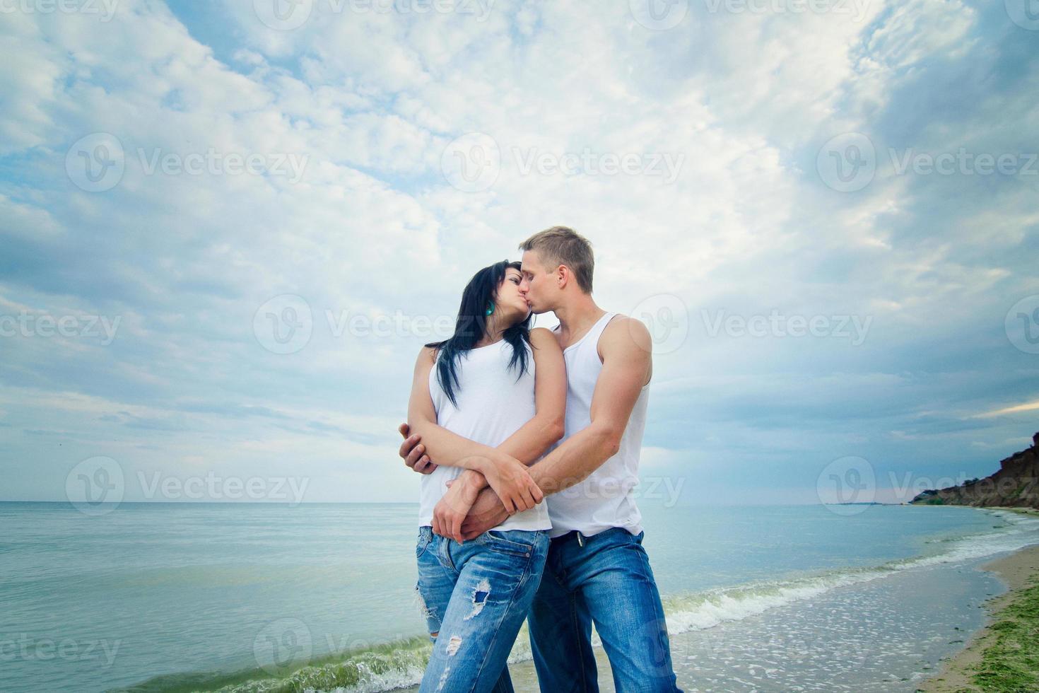 ragazzo e una ragazza in jeans e t-shirt bianche sulla spiaggia foto