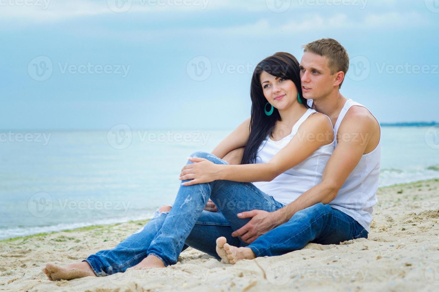 ragazzo e una ragazza in jeans e t-shirt bianche sulla spiaggia foto