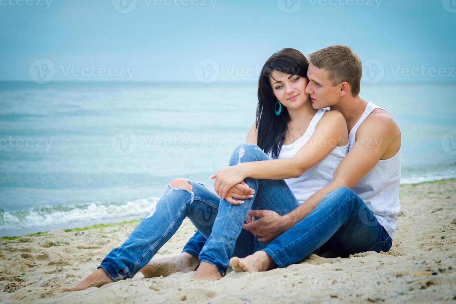 ragazzo e una ragazza in jeans e t-shirt bianche sulla spiaggia foto