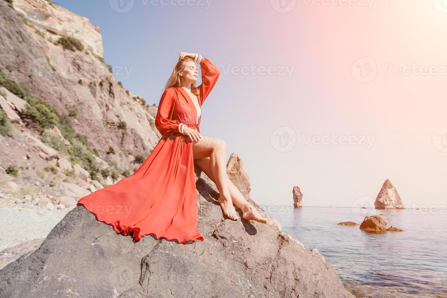 donna viaggio mare. giovane contento donna nel un' lungo rosso vestito in posa su un' spiaggia vicino il mare su sfondo di vulcanico rocce, piace nel Islanda, condivisione viaggio avventura viaggio foto