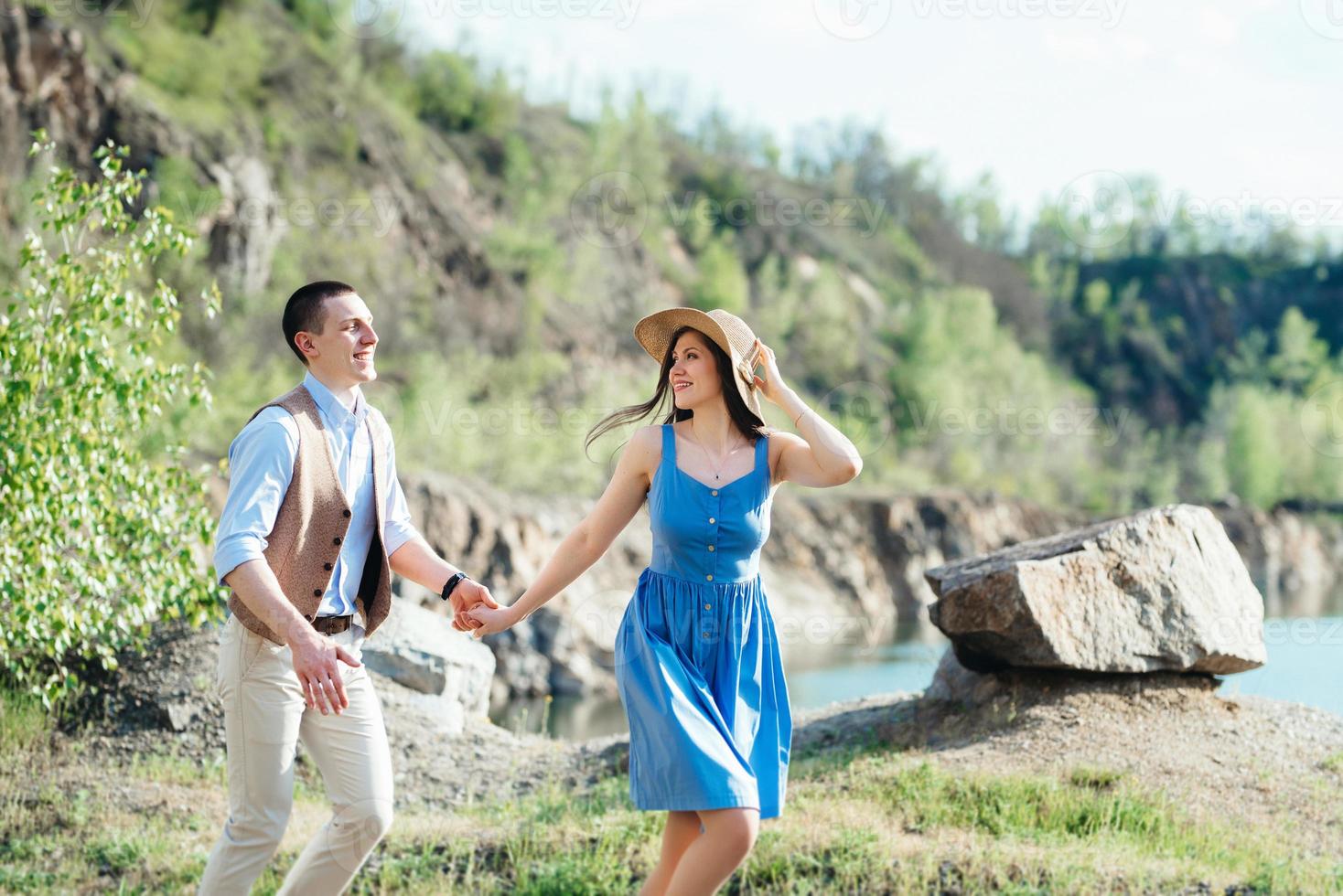 una giovane coppia un ragazzo e una ragazza stanno camminando vicino a un lago di montagna circondato foto