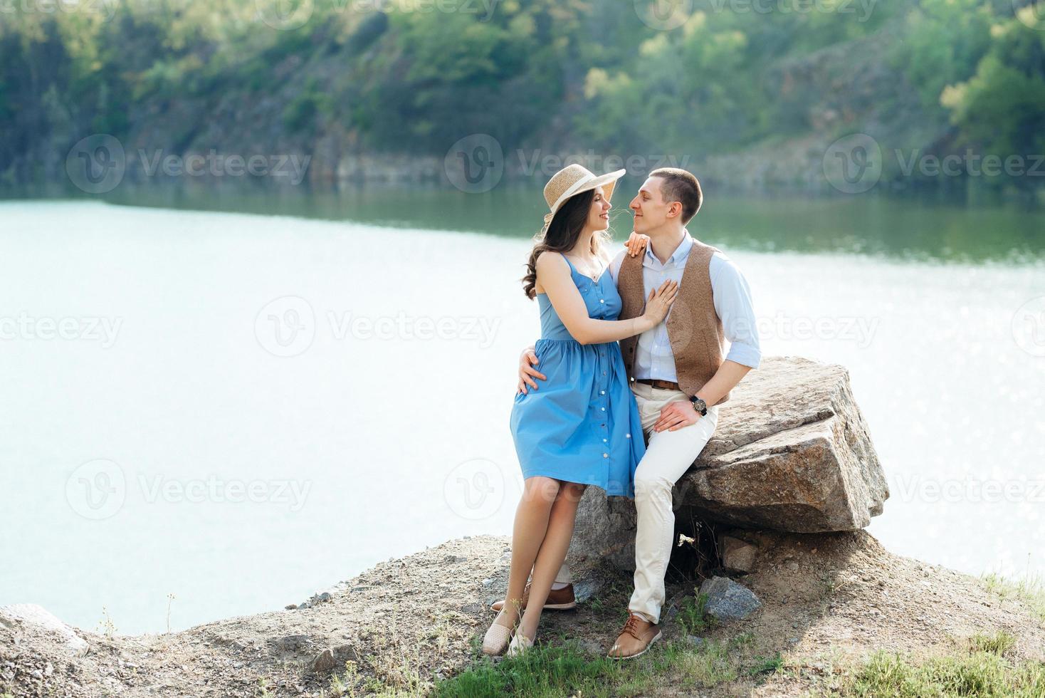 una giovane coppia un ragazzo e una ragazza stanno camminando vicino a un lago di montagna circondato foto