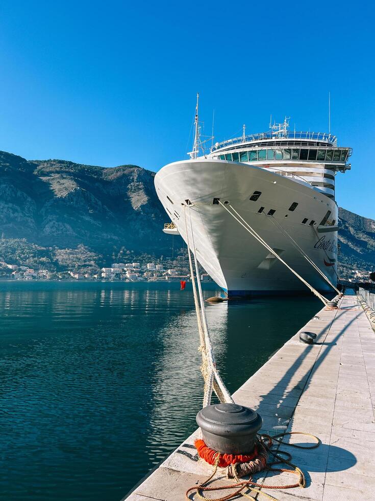 Cattaro, montenegro - 25 dicembre 2022. grande nave è ormeggiato per il ormeggio dissuasori a il molo contro il fondale di il montagne foto