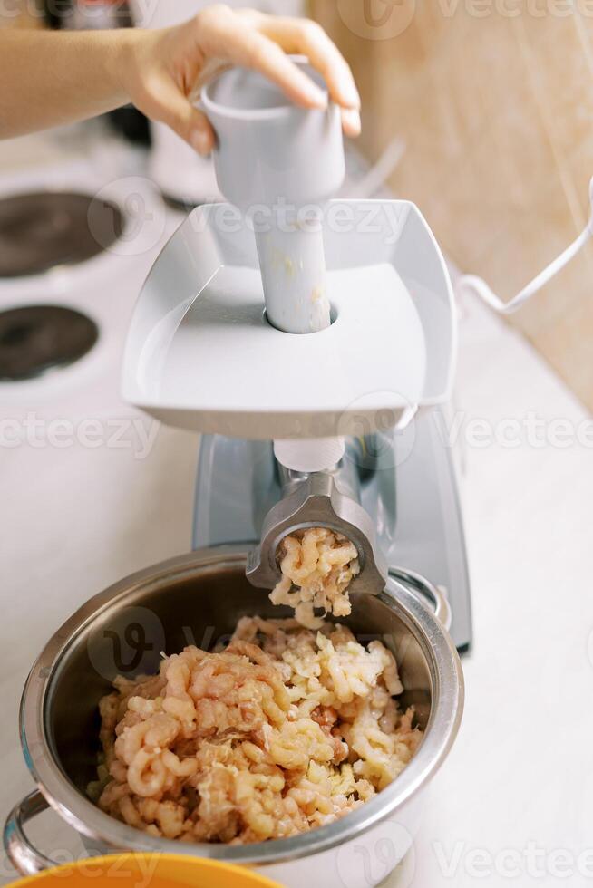 casalinga fa tritato carne su un elettrico carne macinino foto