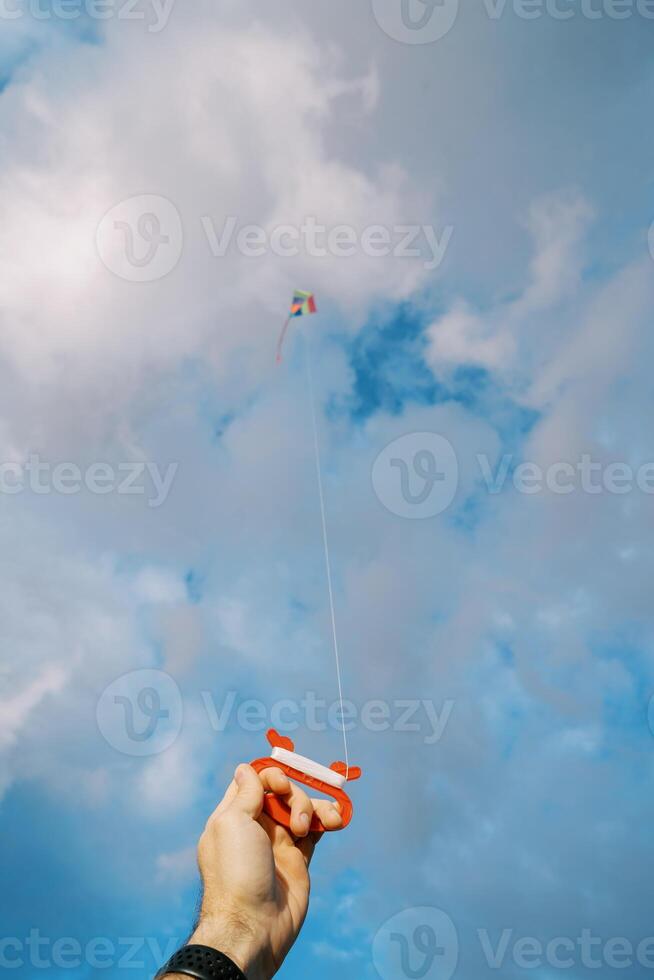 bobina con un' corda con un' aquilone volante nel il cielo nel un' maschio mano foto