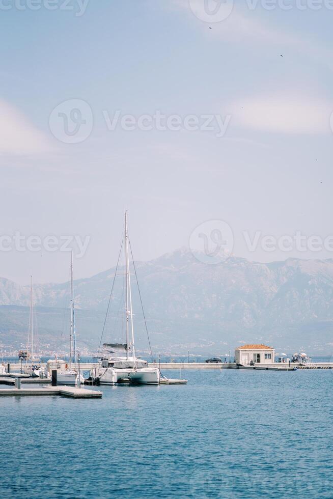 andare in barca catamarano sta a il molo nel il mare contro il fondale di il montagne. indietro Visualizza foto