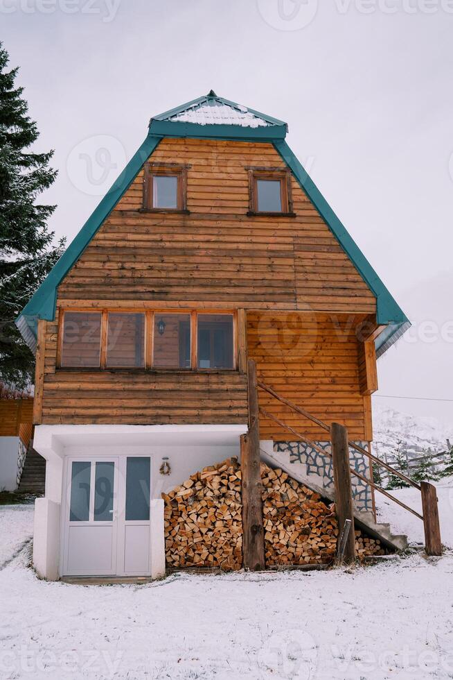 di legno due storie Casa con un' catasta di legna sotto il le scale nel un' nevoso villaggio foto