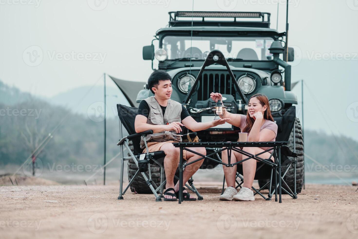 uomo e donna Condividere un' accogliente caffè rompere di un' lago, con un' aspro fuori strada veicolo e campeggio tenda nel il sfondo. foto