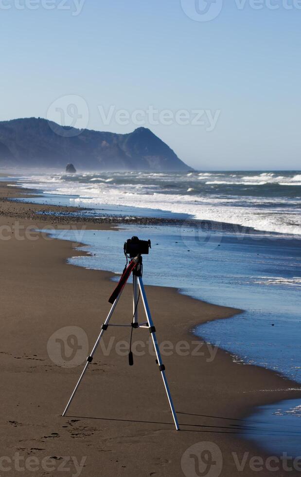 telecamera su tripode su spiaggia con oceano e colline foto