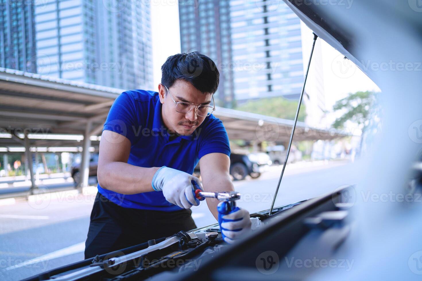 automobile auto concetto. asiatico auto meccanico nel blu uniforme lavori su auto motore riparazione e cliente servizio Lavorando su motori nel il box auto. foto