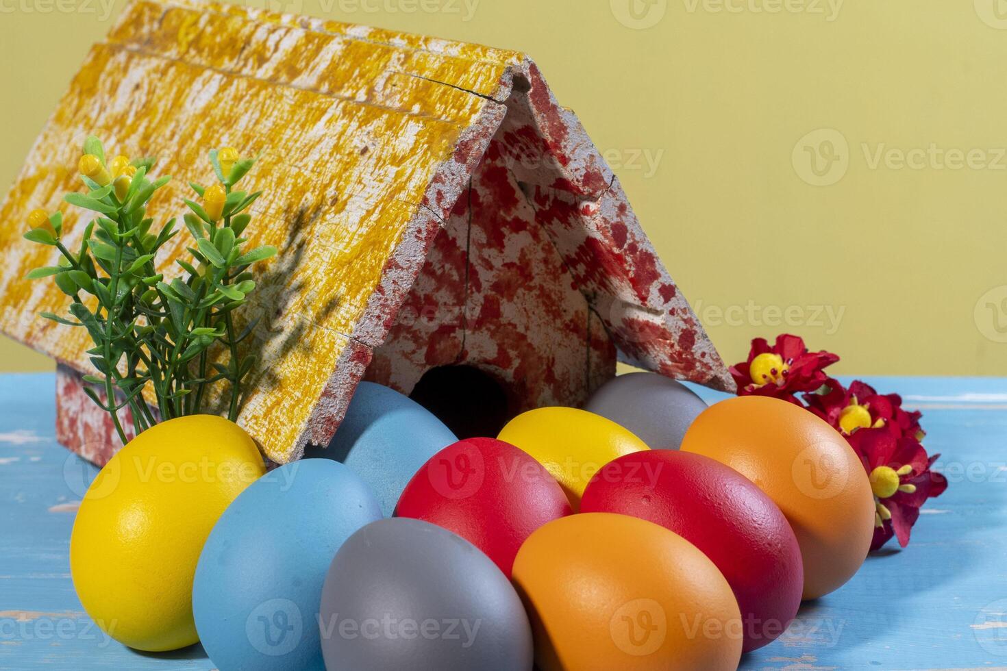 colorato uova simboleggiante Pasqua, con un' giocattolo Casa, fiori piace un' giardino foto