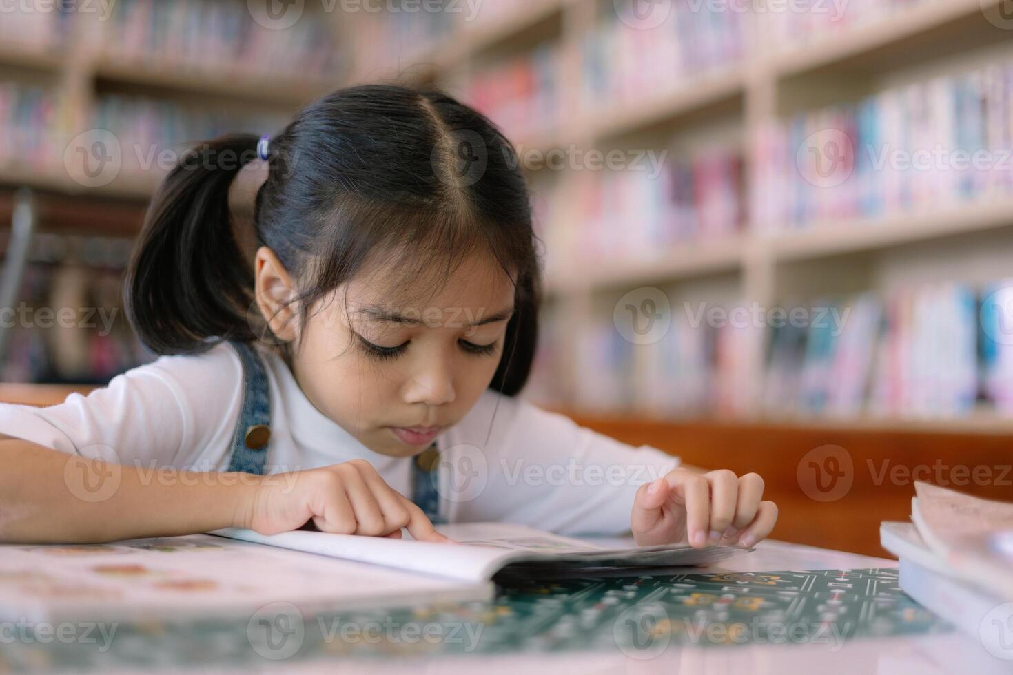 un' giovane ragazza è lettura un' libro nel un' biblioteca foto