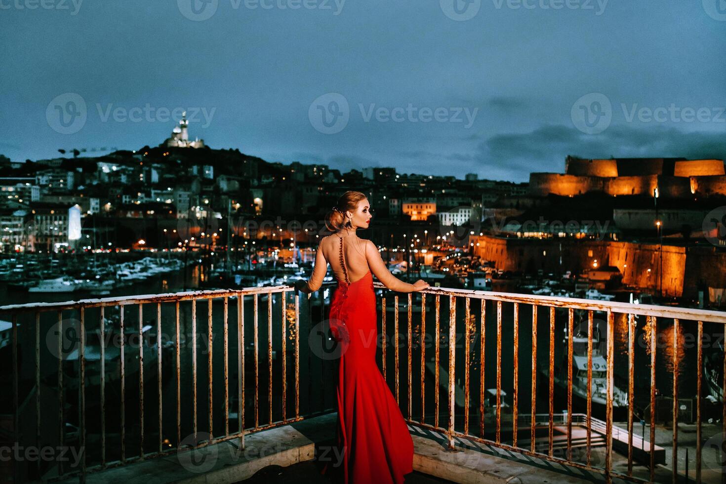 un elegante ragazza nel un' rosso sera vestito su il strade di il notte città di marsiglia.a donna nel un' rosso sera vestito nel Francia foto