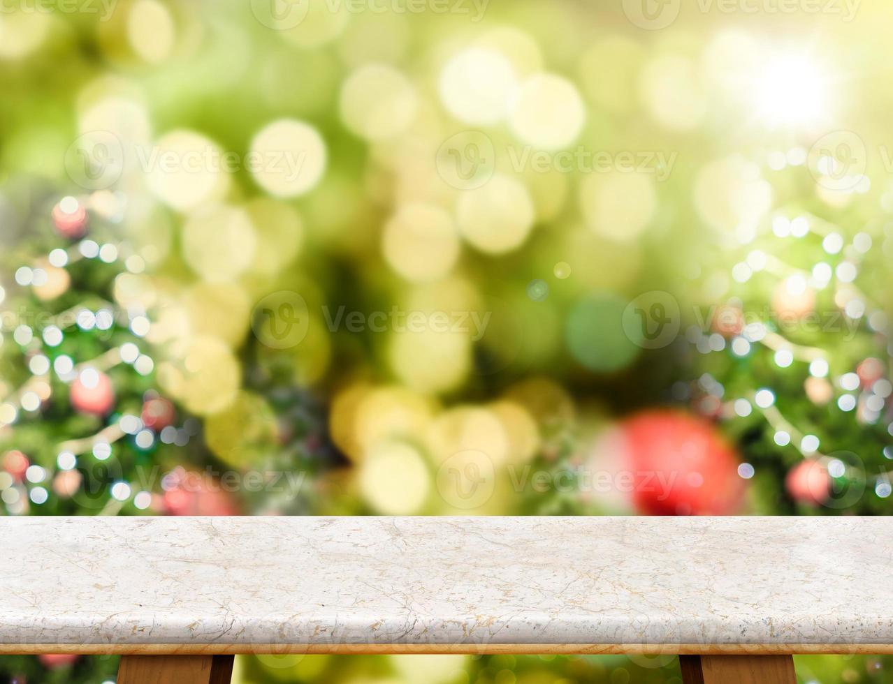 piano del tavolo in marmo con sfocatura astratta dello sfondo dell'albero di Natale con luce bokeh foto