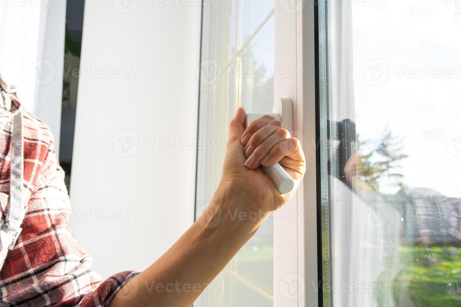 il mano detiene il maniglia di un' plastica doppi vetri finestra, chiusura e apertura il finestra con un' rotante meccanismo, il posizione di il maniglia per ventilazione, microventilazione foto