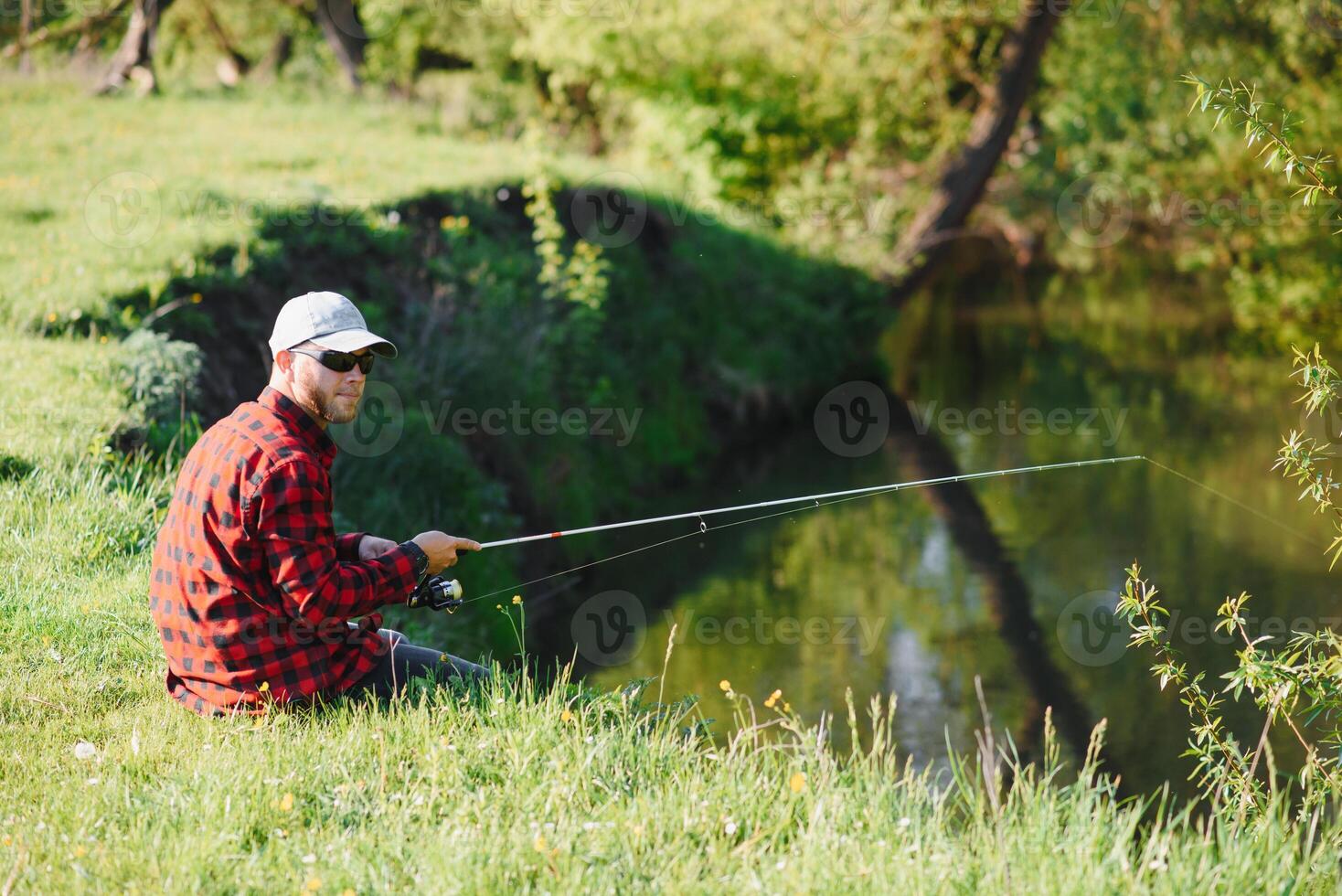 uomo rilassante e pesca di in riva al lago. fine settimana fatto per pesca. pescatore maschile passatempo. maestro adescatore. mantenere calma e pesce Su. pescatore uncinetto rotazione in il fiume in attesa grande pesce. tipo volare pesca foto