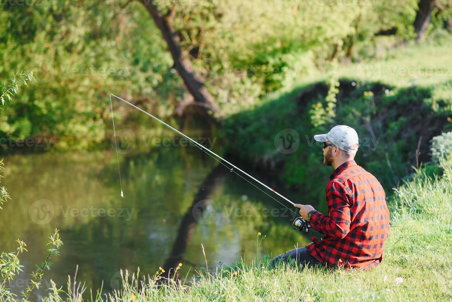 uomo rilassante e pesca di in riva al lago. fine settimana fatto per pesca. pescatore maschile passatempo. maestro adescatore. mantenere calma e pesce Su. pescatore uncinetto rotazione in il fiume in attesa grande pesce. tipo volare pesca foto