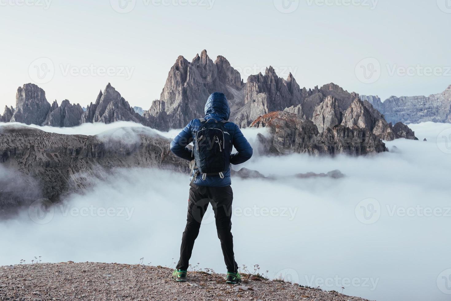 ragazzo in piedi sulla collina e guardando le grandi montagne lontane nella nebbia foto