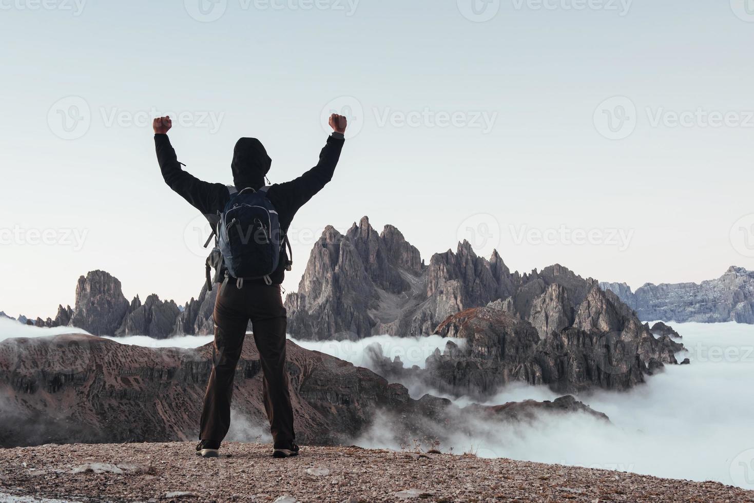 nuovo traguardo. l'uomo turistico ha alzato le mani sulle bellissime montagne diurne piene di nebbia foto