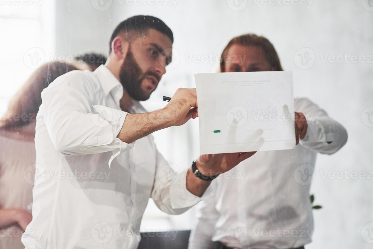 apportare correzioni. persone che lavorano in ufficio e discutono di alcuni dettagli aziendali utilizzando informazioni su carta foto