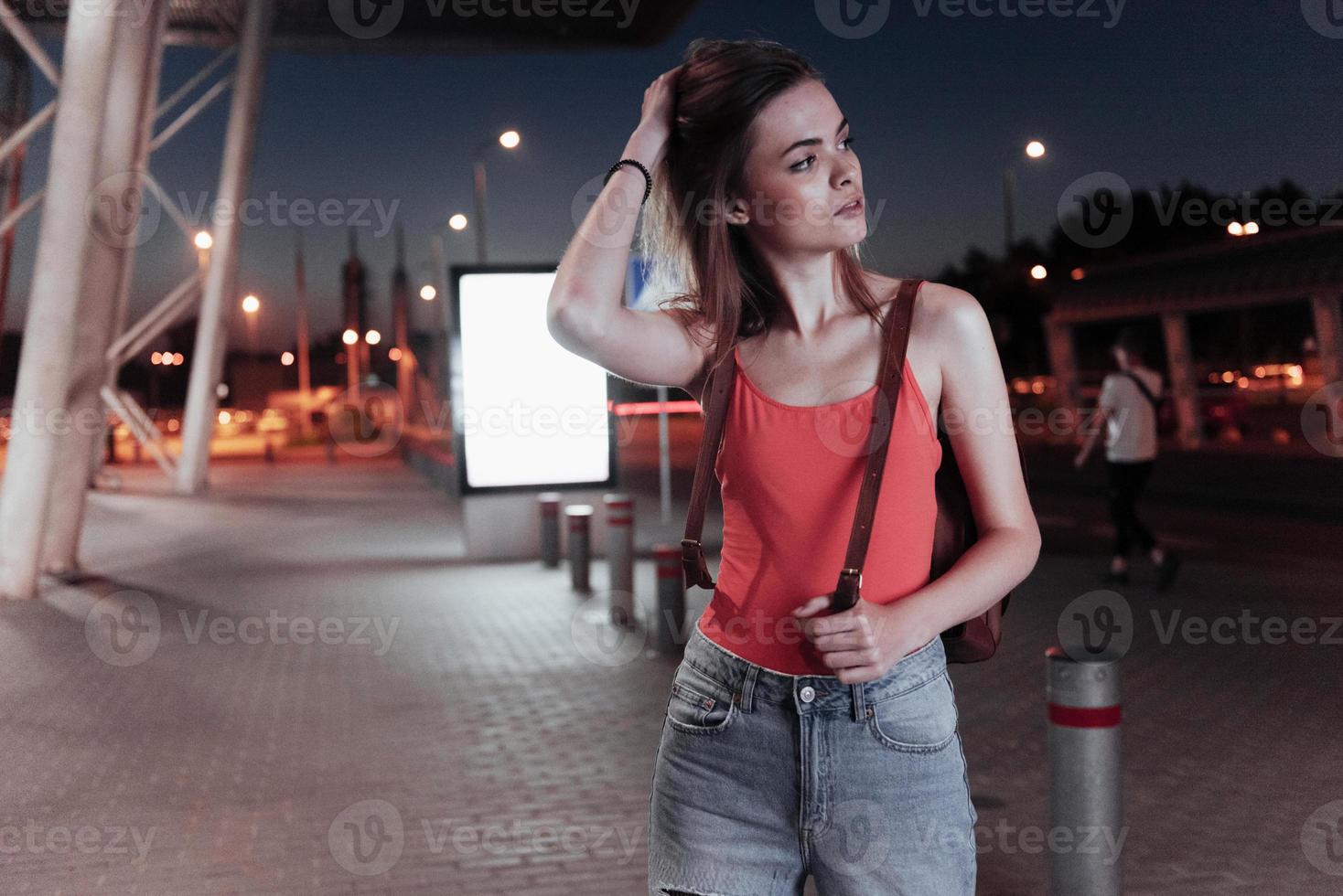 concezione itinerante. donna attraente si aggiusta i capelli con la mano e guarda la strada foto