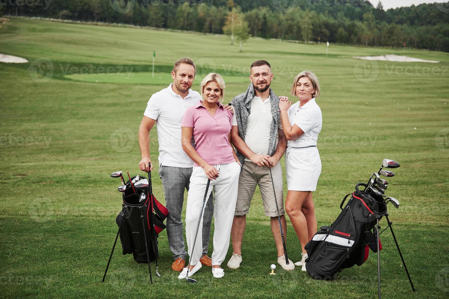 gruppo di amici alla moda sul campo da golf impara a giocare a un nuovo gioco. la squadra si riposerà dopo la partita foto