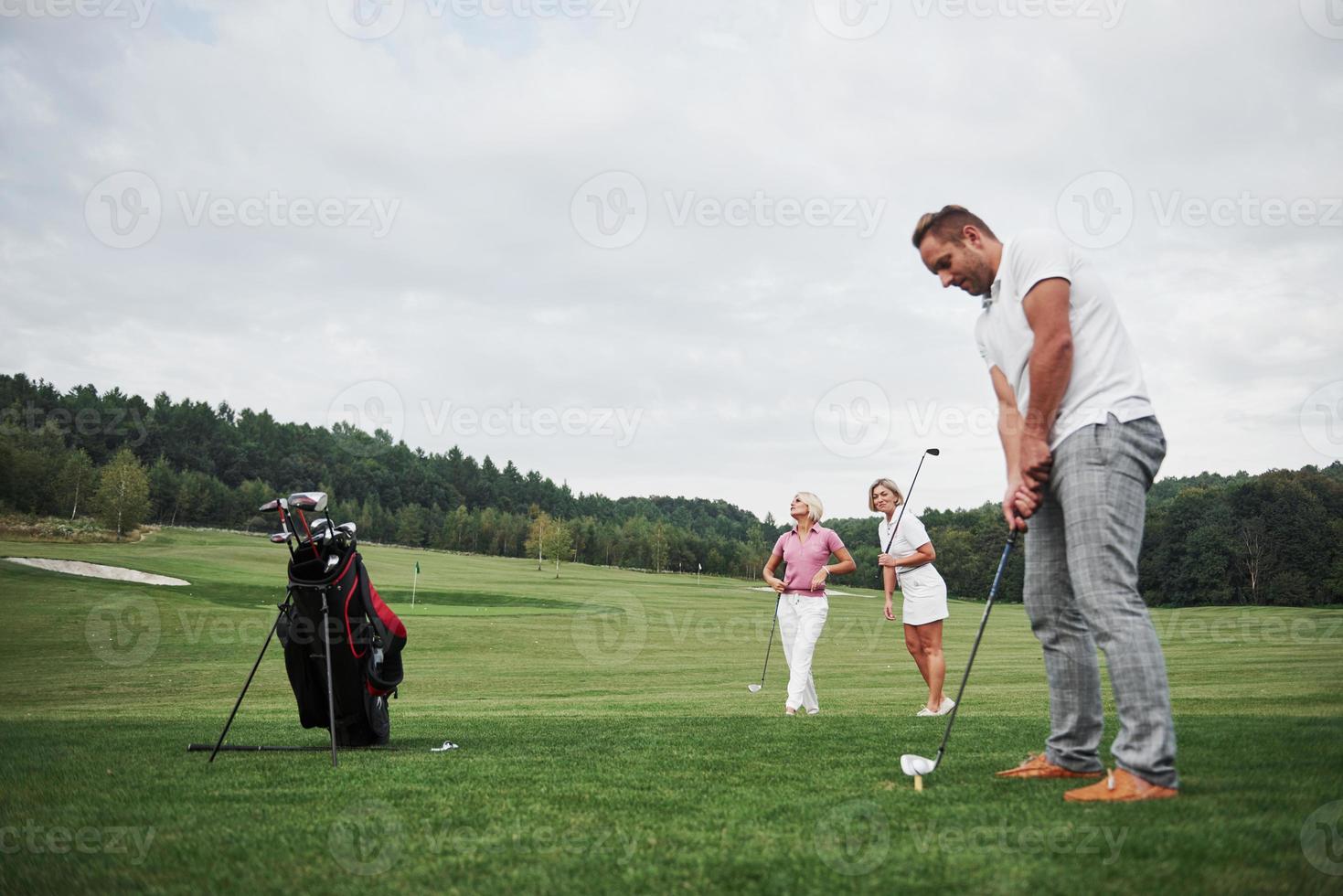 un gruppo di amici alla moda sul campo da golf impara a giocare a un nuovo gioco foto