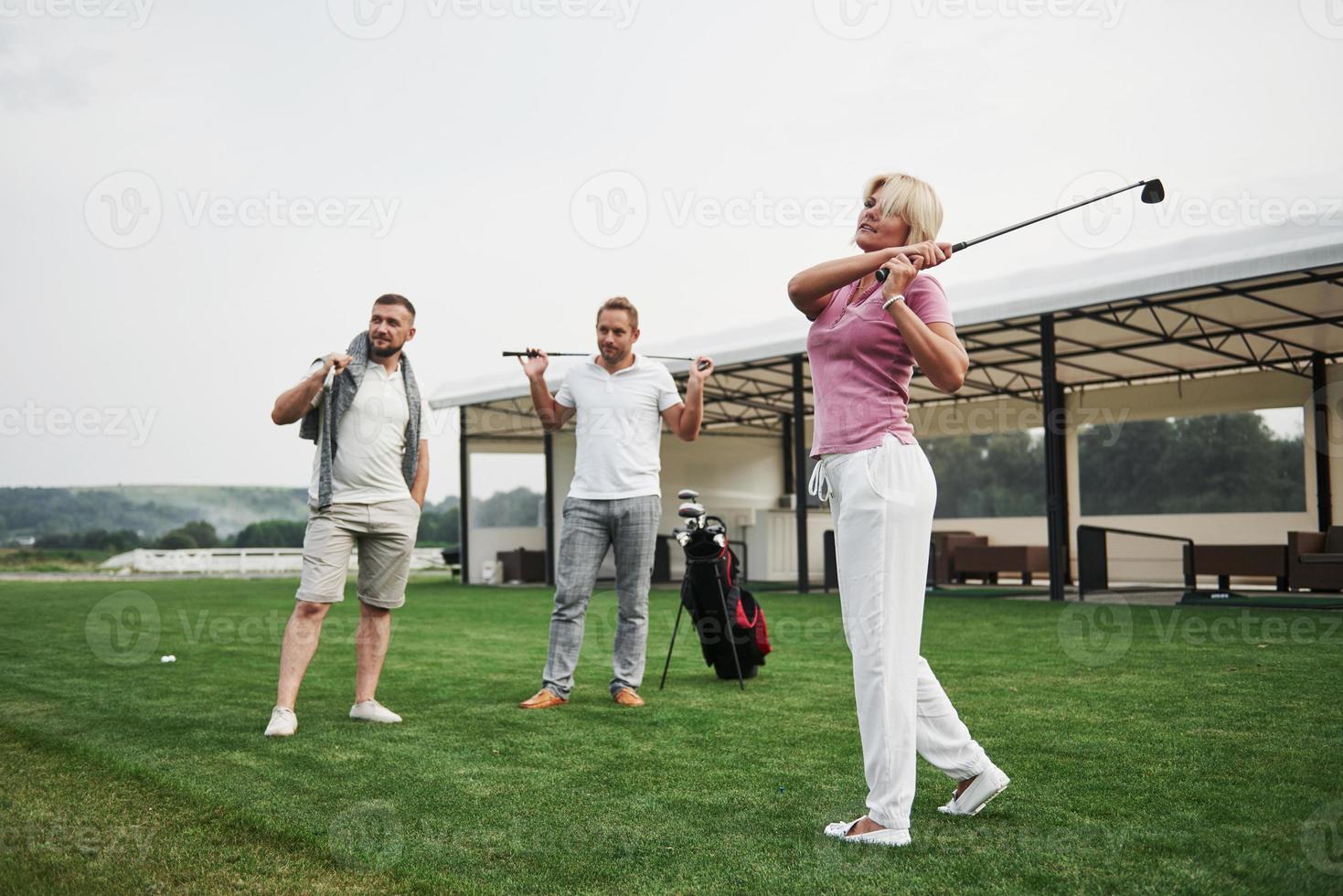 un gruppo di amici alla moda sul campo da golf impara a giocare a un nuovo gioco foto