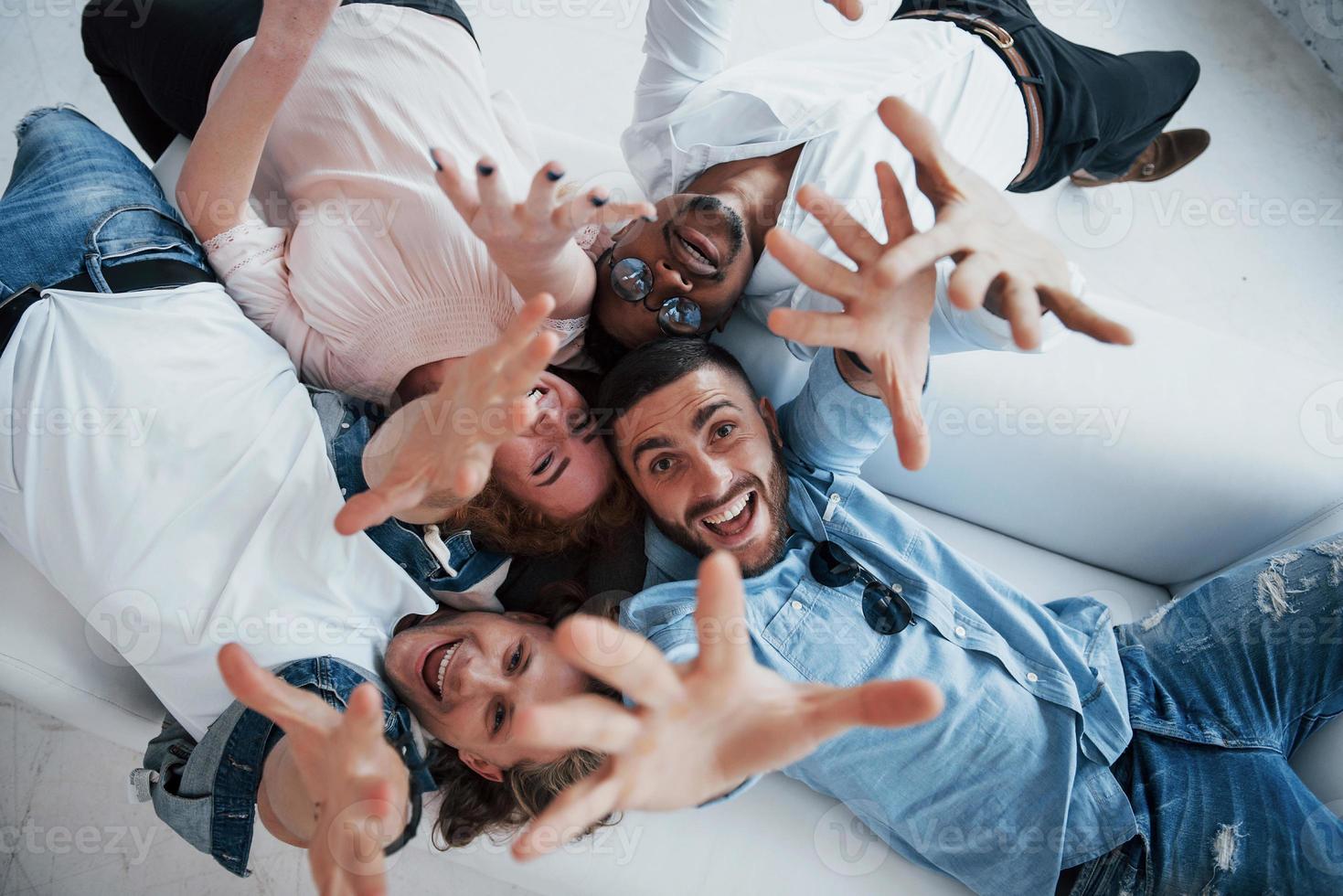 vogliono raggiungerti. giovani sdraiati e sorridenti alla telecamera foto