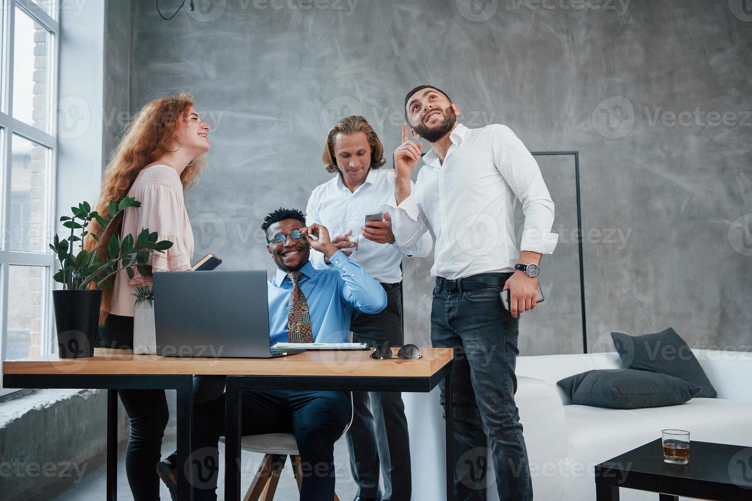 nuove idee stanno arrivando. l'uomo fa dei gesti. gruppo di impiegati multirazziali in abiti formali che parlano di compiti e piani foto