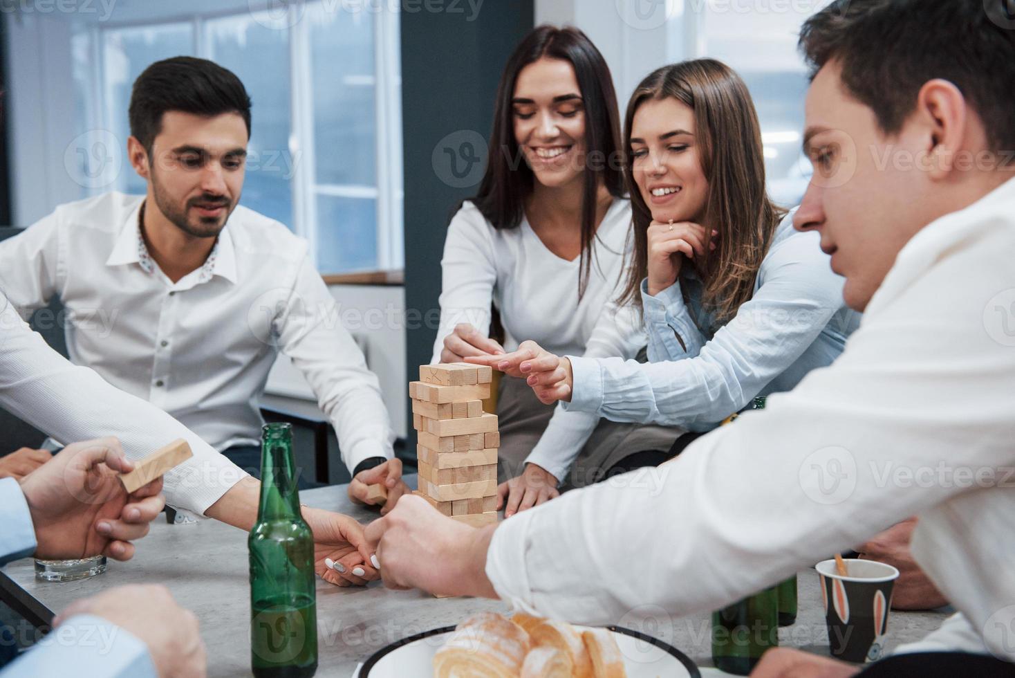 giocando in giro. festeggiare l'affare riuscito. giovani impiegati seduti vicino al tavolo con l'alcol foto