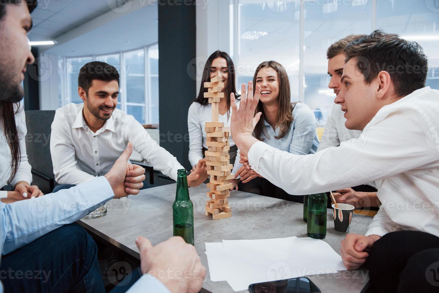 per favore non cadere. festeggiare l'affare riuscito. giovani impiegati seduti vicino al tavolo con l'alcol foto